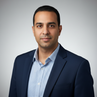 מודל גבר, הבעה בטוחה ונינוחה; לבוש בלייזר כחול כהה וחולצה מכופתרת פסים עדינה בגווני תכלת-לבן, פתוחה בצווארון; רקע אפור-בהיר מטושטש עם מעבר גוונים עדין; תאורה קדמית רכה, אווירה מקצועית ונגישה.התמונה תכיל רק אדם אחד.